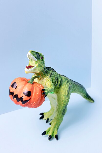 Close-up halloween dinosaurio juguete sosteniendo calabaza