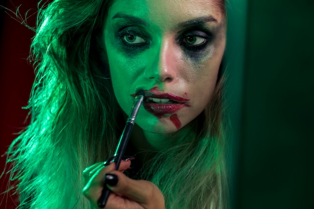 Close-up halloween girl usando un cepillo para sus labios