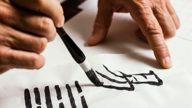 Foto gratuita close-up de hombre escribiendo símbolos chinos sobre papel blanco