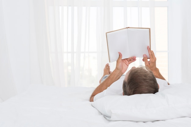 Close-up hombre leyendo en el dormitorio