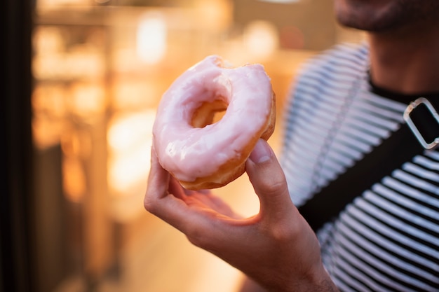 Close-up hombre sosteniendo donut glaseado