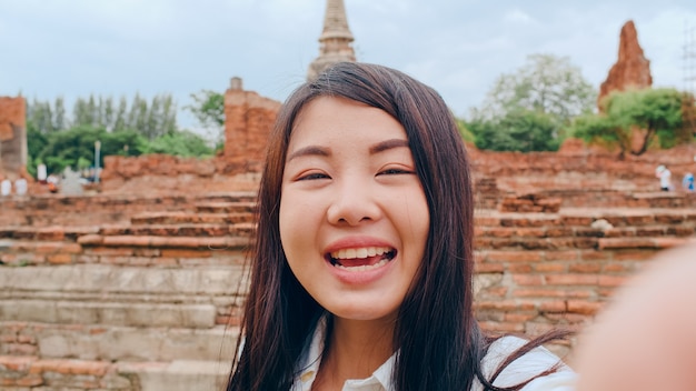 Close-up joven asiática mochilero blogger mujer mira al frente en el teléfono inteligente