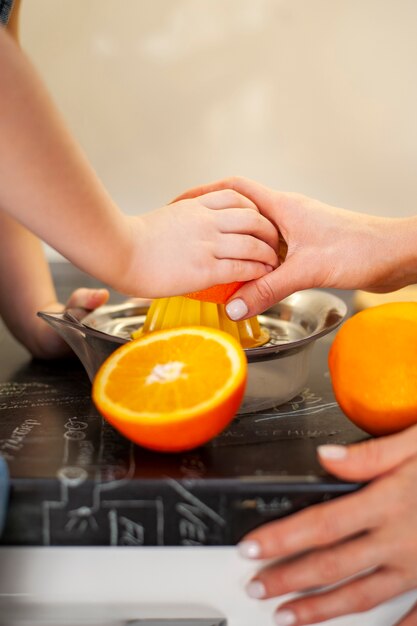 Close-up joven y madre preparando jugo de naranja
