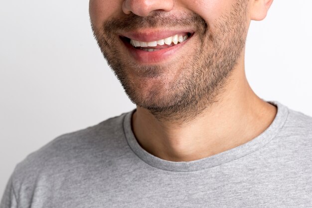 Close-up de joven sonriente en camiseta gris sobre fondo blanco.