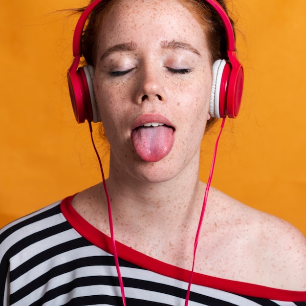 Close-up linda mujer con lengua afuera y auriculares