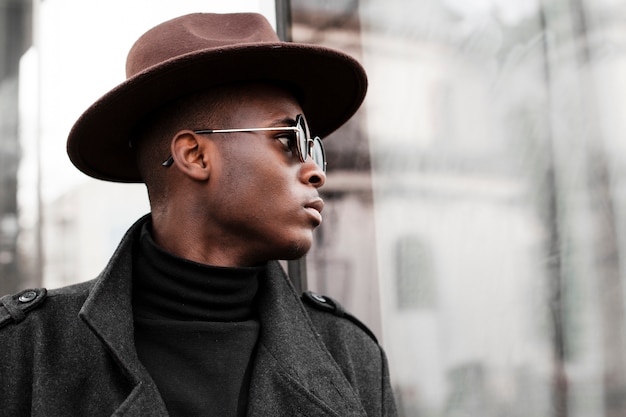 Close-up macho adulto con sombrero moderno y gafas de sol