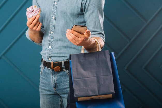 Close-up macho adulto sosteniendo bolsas de compras