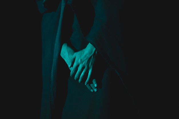 Close-up de mano sujetando juntos en la oscuridad