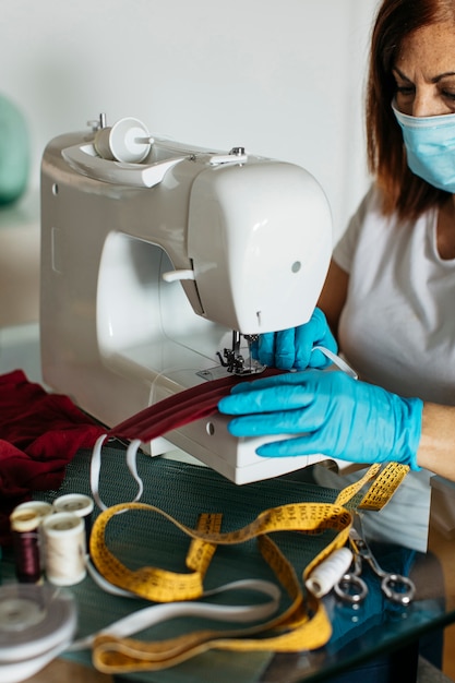 Close-up de manos con guantes cosiendo máscaras de tela