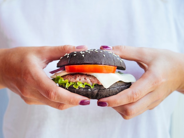 Close-up manos mostrando sabrosa hamburguesa