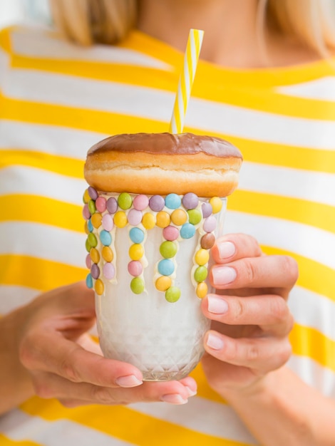 Close-up manos sosteniendo batido con donut