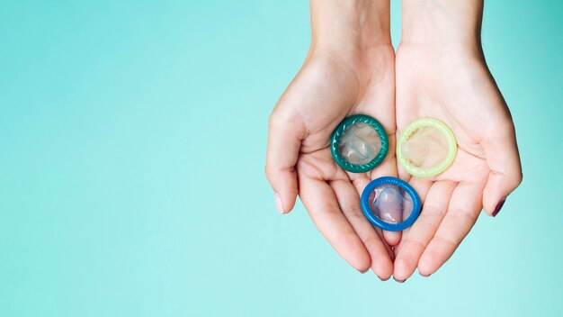 Close-up manos sosteniendo condones con fondo azul