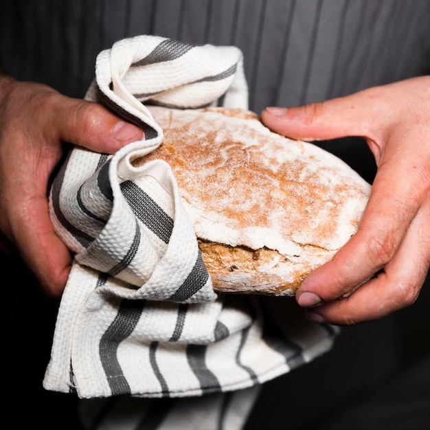Close-up manos sosteniendo una hogaza de pan