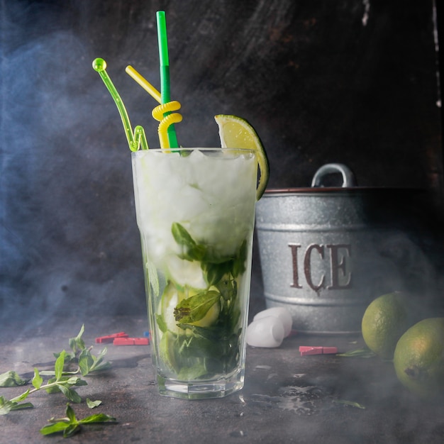 Close-up mojito cocktail con menta, lima, hielo, cubo de hielo con humo