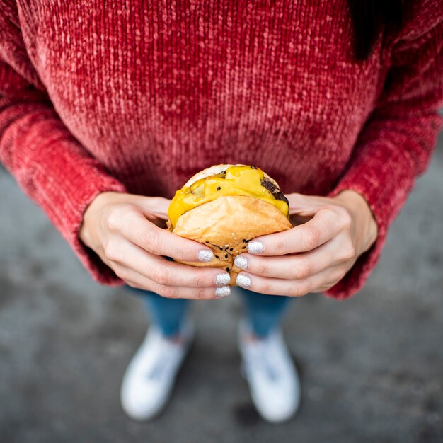 Close-up mujer con ángulo alto de hamburguesa con queso