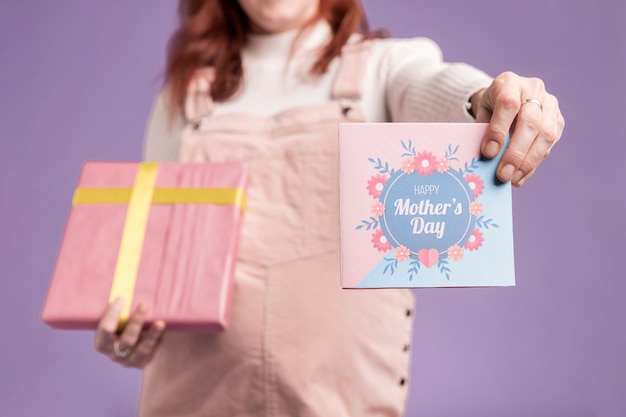 Close-up mujer embarazada mostrando regalo y tarjeta de felicitación