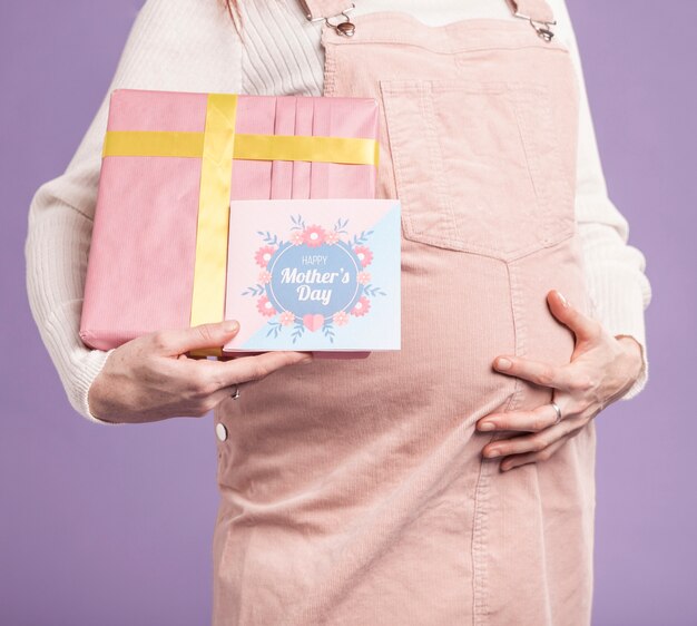 Close-up mujer embarazada con regalo y tarjeta de felicitación