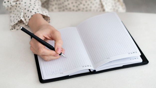 Foto gratuita close-up mujer escribiendo en el cuaderno