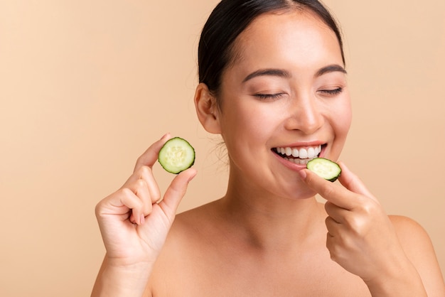 Close-up mujer morena mordiendo rodaja de pepino