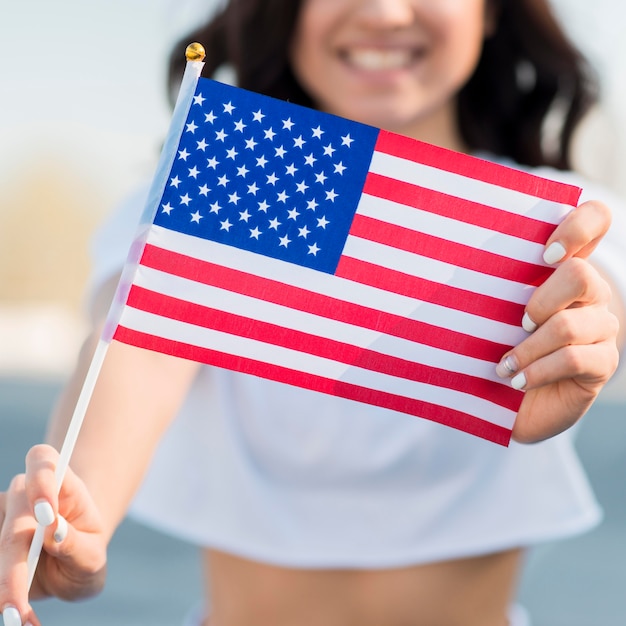 Close-up mujer sonriendo sosteniendo la bandera de Estados Unidos