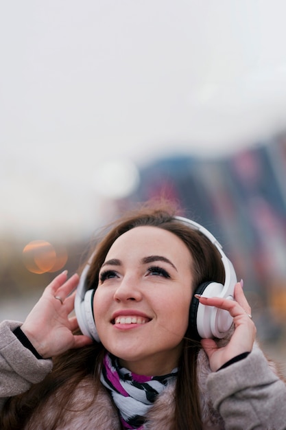 Close-up mujer sonriente con auriculares mirando hacia arriba