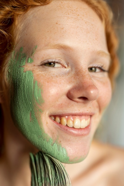 Close-up mujer sonriente pintando su rostro