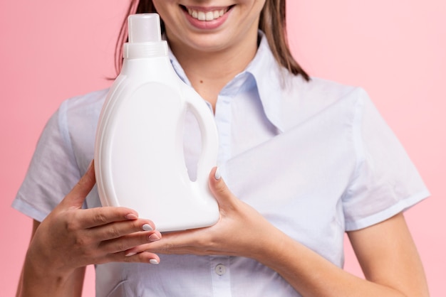 Close-up mujer sonriente sosteniendo la botella de detergente