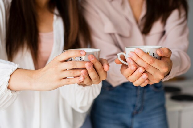 Close-up mujeres sosteniendo tazas con café