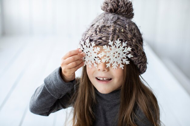 Close-up niña cubriéndose la cara con copos de nieve