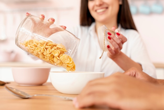 Close-up niña sonriente vertiendo cereales en un tazón