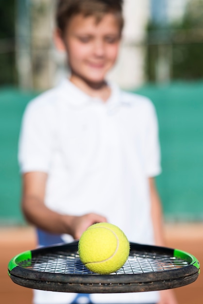 Foto gratuita close up niño sosteniendo la pelota en la raqueta
