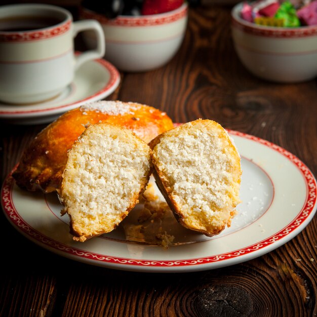 Close-up panadería casera con taza de té, dulces y bayas en la mesa de madera