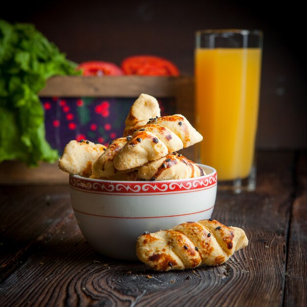 Close-up panadería casera con taza de té, jugo de naranja y tomate en mesa de madera