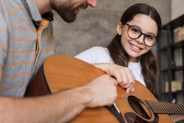 Close-up papá enseñando a niña a tocar la guitarra