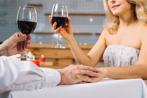 Close-up de pareja cogidos de la mano en una cena romántica