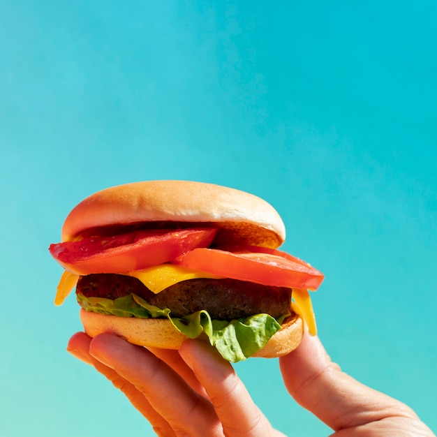 Close-up persona sosteniendo una hamburguesa con queso