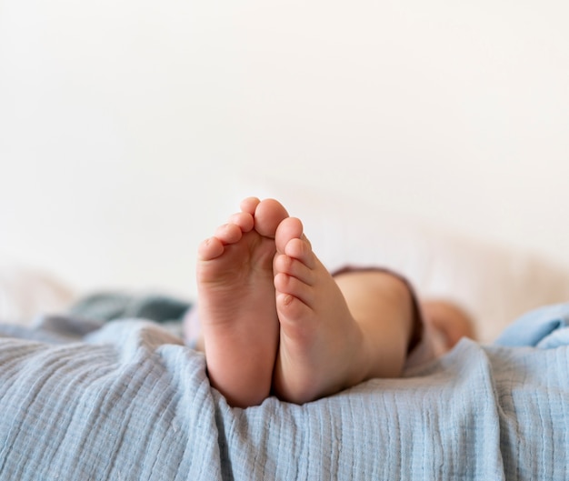 Close-up pies de bebé sentado en la cama