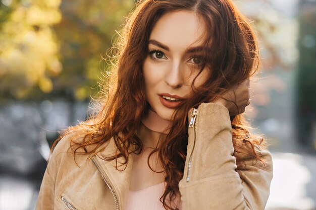 Close-up retrato al aire libre de hermosa mujer jengibre con ojos grandes lleva chaqueta beige