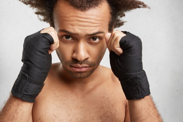 Close Up retrato de boxeador masculino exitoso muestra brazos fuertes y puños cerrados envueltos por vendas protectoras