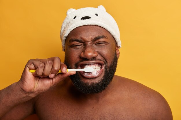 Close Up retrato de hombre afro negro cepilla los dientes, tiene rutina diaria por la mañana