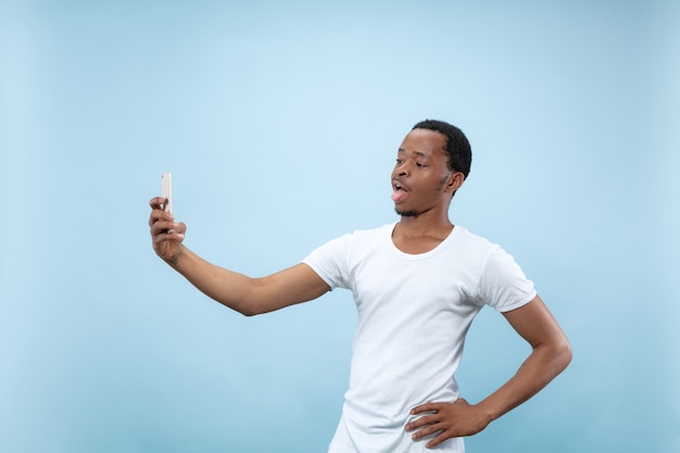 Close up retrato de joven afroamericano con camisa blanca ... Haciendo selfie o contenido para redes sociales, vlog.