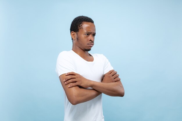 Close up retrato de joven afroamericano con camisa blanca. Manos de pie cruzadas y tristes, molestas o tranquilas.
