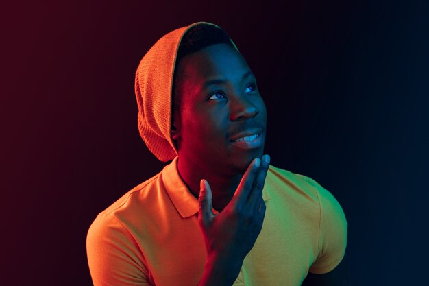 Close Up retrato de un joven afroamericano feliz sonriendo contra el fondo de estudio de neón negro