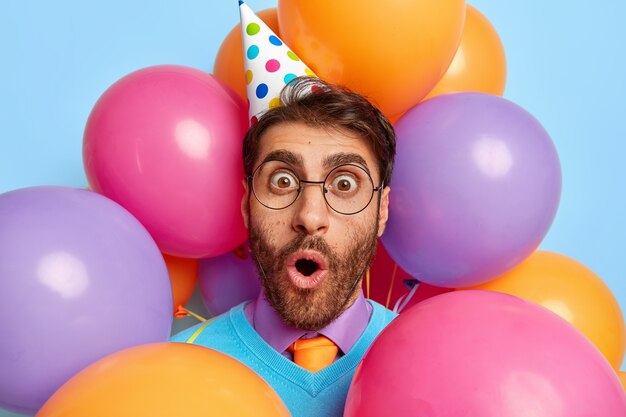 Close Up retrato de joven rodeado de globos de fiesta posando