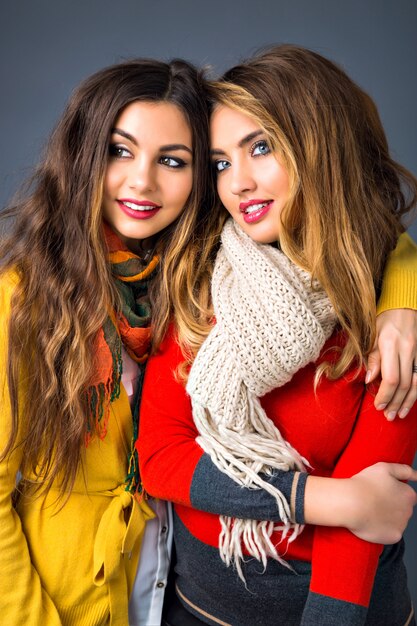 Close up retrato de lindas chicas rubias y morenas, abrazos, estilo de familia hermana, temporada otoño invierno, vistiendo suéteres y bufandas