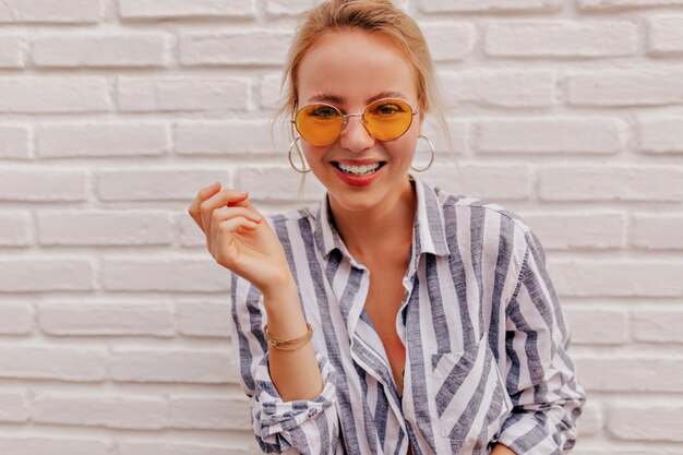 Close Up retrato de mujer atractiva con maravillosa sonrisa con gafas naranjas y camisa despojada