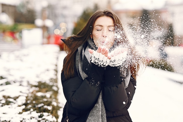 Foto gratuita close-up retrato de mujer con chaqueta negra jugando con la nieve.