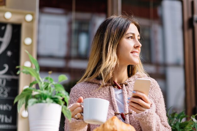 Close Up retrato de mujer de estilo joven está sentado en la cafetería en la calle