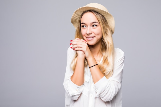 Close Up retrato de una mujer joven sonriente con sombrero mirando a otro lado en el espacio de copia aislado sobre pared gris