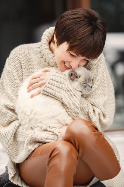 Close-up retrato de mujer en suéter blanco con gato blanco